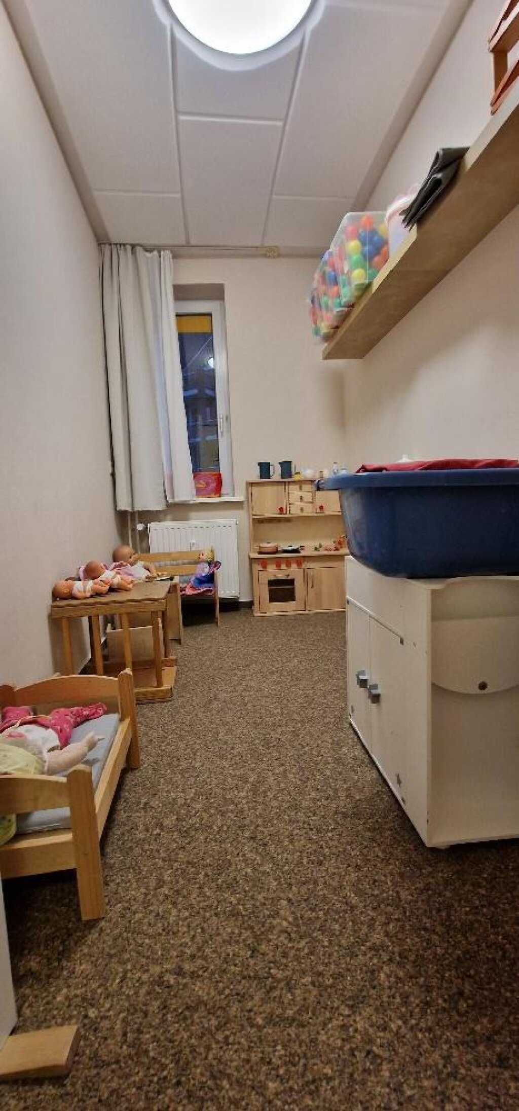 Gruppenraum der AWO Kita Chi-Kita mit Kinderküche und Puppenbett.